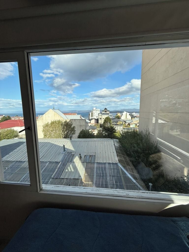 A room with a large window overlooking a cityscape, including buildings and a road.