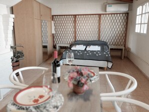 Une pièce avec un lit, une table sur laquelle se trouvent une bouteille et des verres, et une chaise.