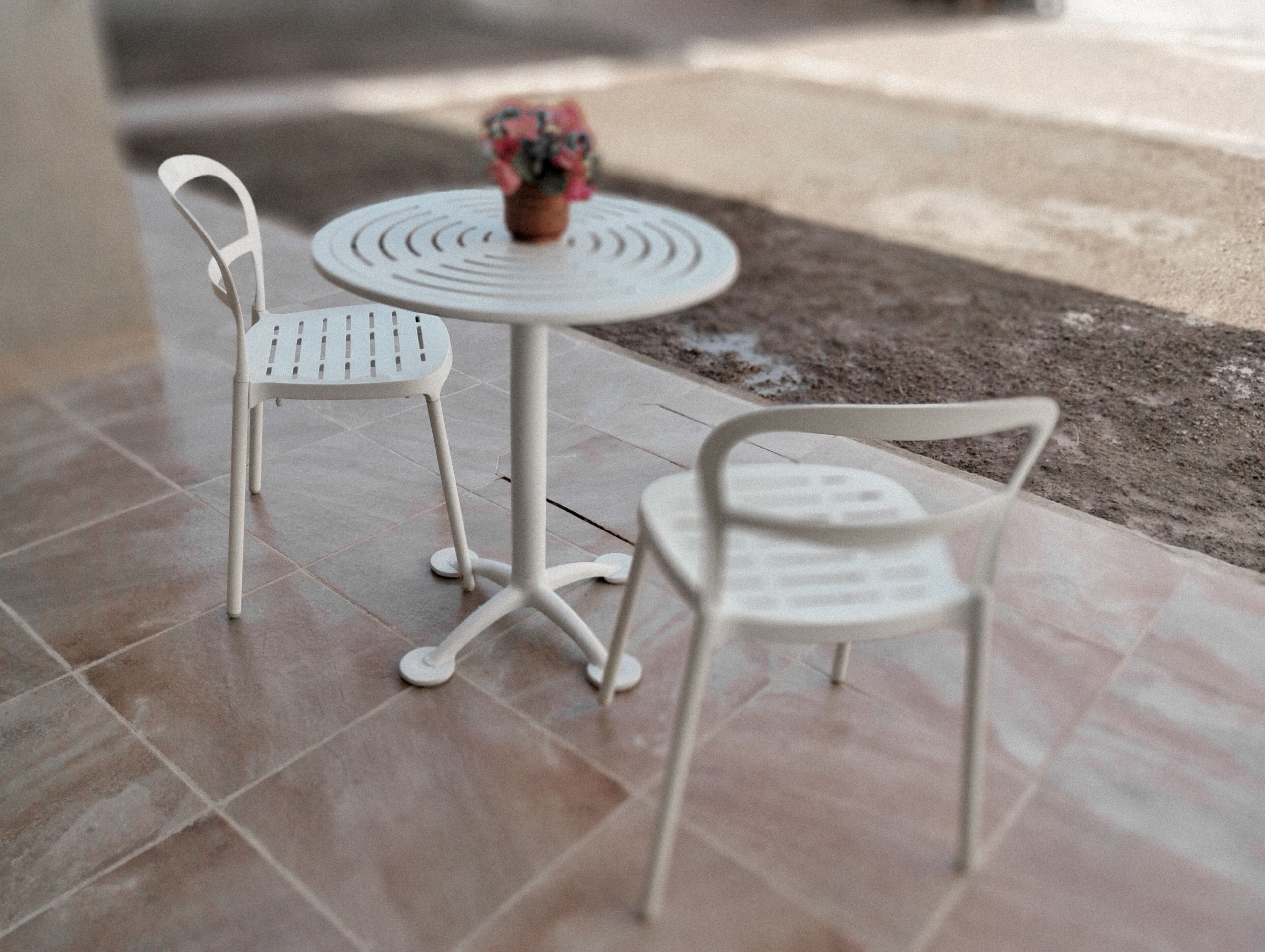 A small outdoor seating area with a round table and two white chairs.