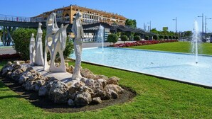 A fountain with abstract sculptures in a park area, a bridge, and a building with multiple windows in the background. - Lovely apartment for 2 people with WIFI, A/C, TV and terrace (Marbella)