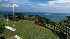 Uma área gramada com baloiço e vista para a costa.