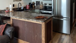 Una cocina con una isla central, electrodomésticos de acero inoxidable y un techo rústico.