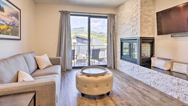 A modern living room with a sofa, ottoman, and a fireplace.