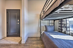 Cozy bedroom with a bunk bed arrangement, featuring a bed with a quilted cover and pillows, and a metal-framed bunk bed.