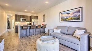 A modern kitchen with a central island, bar stools, and a dining area.