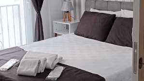 A modern bedroom with a bed, dark curtains, a bedside table with a lamp, and a striped wall. - Maxxmarine hotel (Izmir)