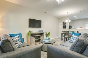 A modern living room with a grey sofa set, a coffee table, and a flat-screen TV mounted on the wall. - Pets Welcome: Townhome w/ Patio in Raleigh! (Raleigh)