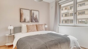 Een moderne slaapkamer met een groot bed, twee bedlampen en kunst aan de muur.