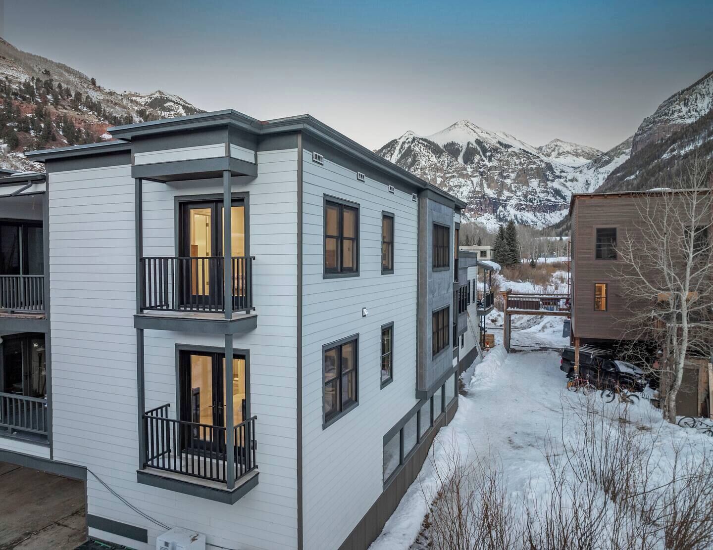 A modern multi-story building with balconies, situated in a snowy mountainous area.