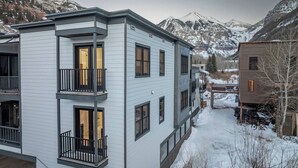 Un moderno edificio de varios pisos con balcones, ubicado en una zona montañosa nevada.