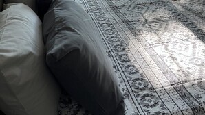 A bedroom with a bed, pillows, and a view of a wooden deck through a window. - Home in the Center of the City! (Alexandria)