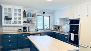 Une cuisine moderne avec des armoires bleues, un plan de travail en bois et un mur de fond en briques.