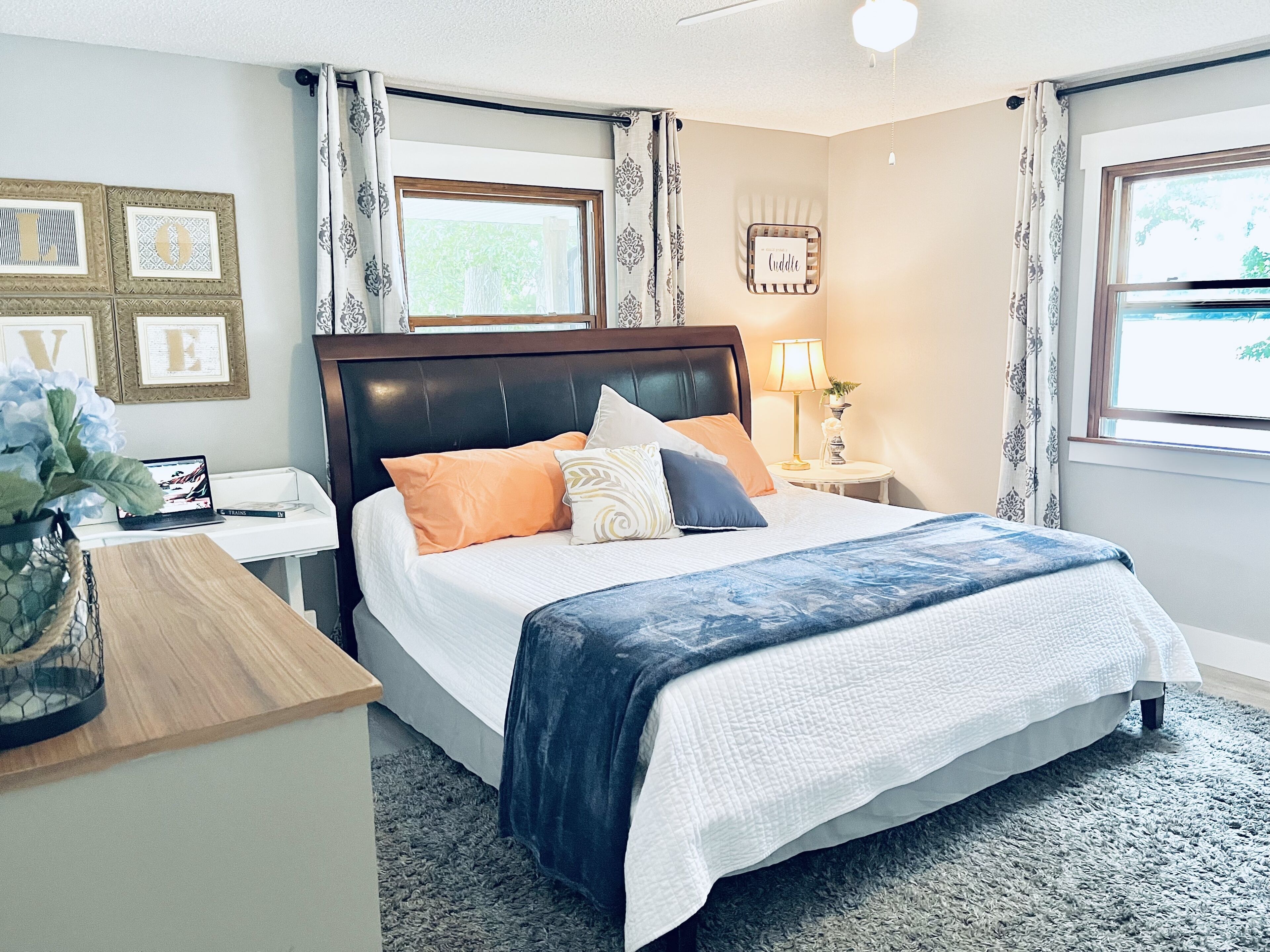 A neatly arranged bedroom with a bed, bedside tables, a lamp, and a window with curtains.