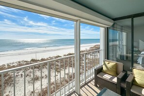 Een balkon met uitzicht op strand en zee.