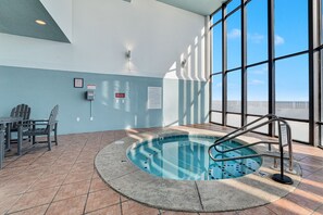 Ein Hallenbad mit gefliestem Boden, einer Poolleiter und einem Tisch mit Stühlen.
