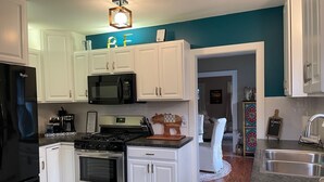 Una cocina moderna con armarios blancos, un refrigerador negro, un microondas, una estufa y un lavaplatos.