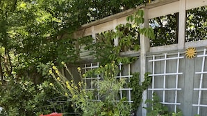 Un jardin avec des plates-bandes surélevées, un treillage en bois et une statue.