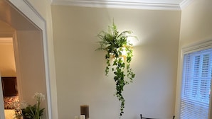 Un petit coin repas avec une table ronde, deux chaises, une bougie et une plante suspendue.
