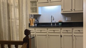 Une cuisine avec des meubles blancs, un plan de travail noir et une fenêtre au-dessus de l’évier.