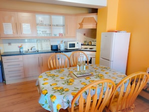 A kitchen with wooden cabinets, a microwave, a stove, and a dining table with chairs.