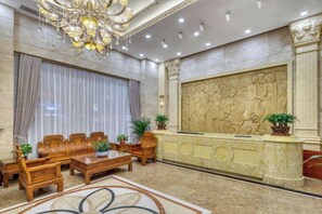 A lobby with a reception desk, seating area, and a chandelier.
