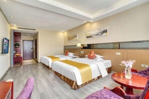 A hotel room with two beds, a small table, and a chair.
