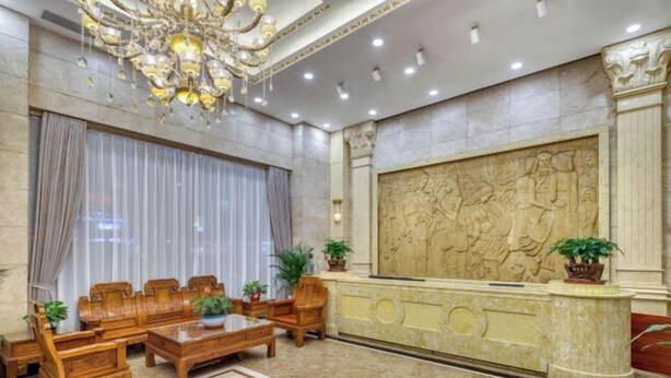 A lobby with a reception desk, wooden furniture, a chandelier, and a large decorative wall. - Zhongshan Union Hotel (Zhongshan)