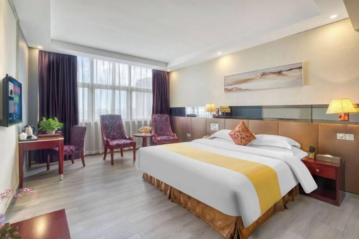 Habitación de hotel con una cama grande, dos sillas, un escritorio y una mesita de noche.