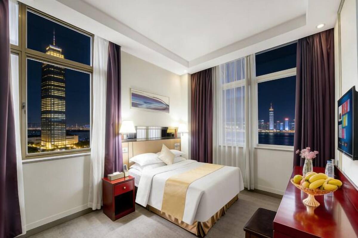 Una habitación de hotel con cama, mesita de noche y escritorio con frutero.