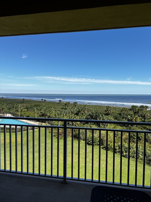 A balcony with a view of the ocean and a grassy area.