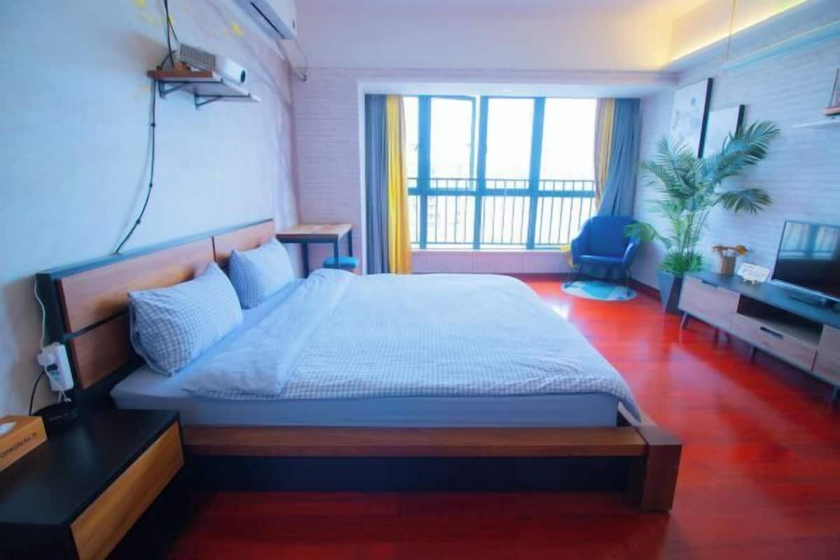 Une chambre d’hôtel avec un lit, une télévision, un bureau, une chaise et une fenêtre avec des rideaux.