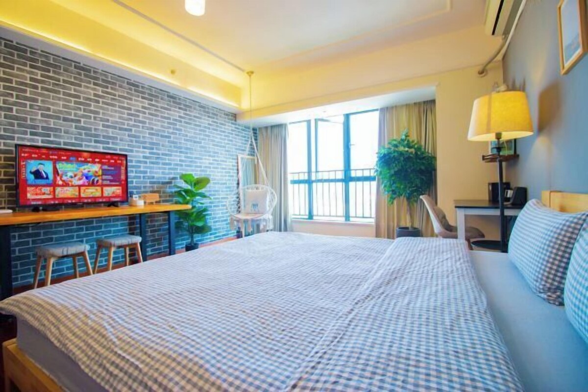 Habitación de hotel con una cama grande, un escritorio con ordenador, televisión y balcón con vistas.