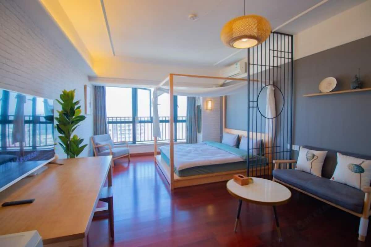 Une chambre d’hôtel moderne dotée d’un grand lit, d’un bureau, d’une table ronde, d’un canapé et d’une grande fenêtre donnant sur la ville.