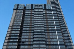 A tall, modern building with a grid of windows and a prominent vertical line running down the center. - Huizhou Kaisa Musi Hotel Apartment (Huizhou)