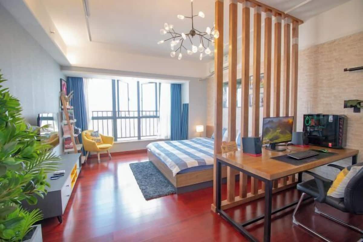 Une chambre moderne avec un lit, un bureau, un ordinateur et une grande fenêtre.