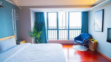 Una habitación de hotel con una cama, una silla, un ventanal grande y una planta.