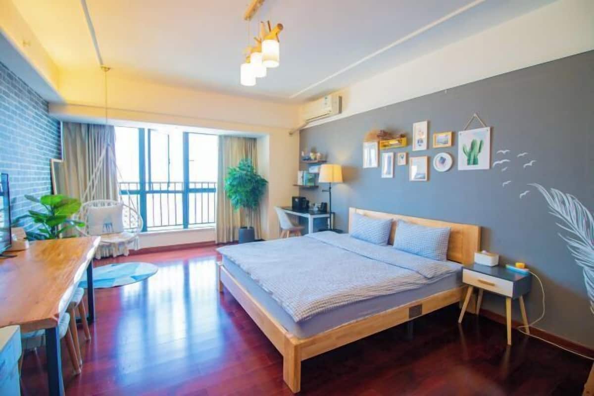 Une chambre d’hôtel moderne, dotée d’un grand lit, d’un bureau, d’une chaise et offrant une vue sur l’extérieur.