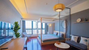 A modern hotel room with a bed, a desk, a sofa, and a large window. - Huizhou Kaisa Musi Hotel Apartment (Huizhou)