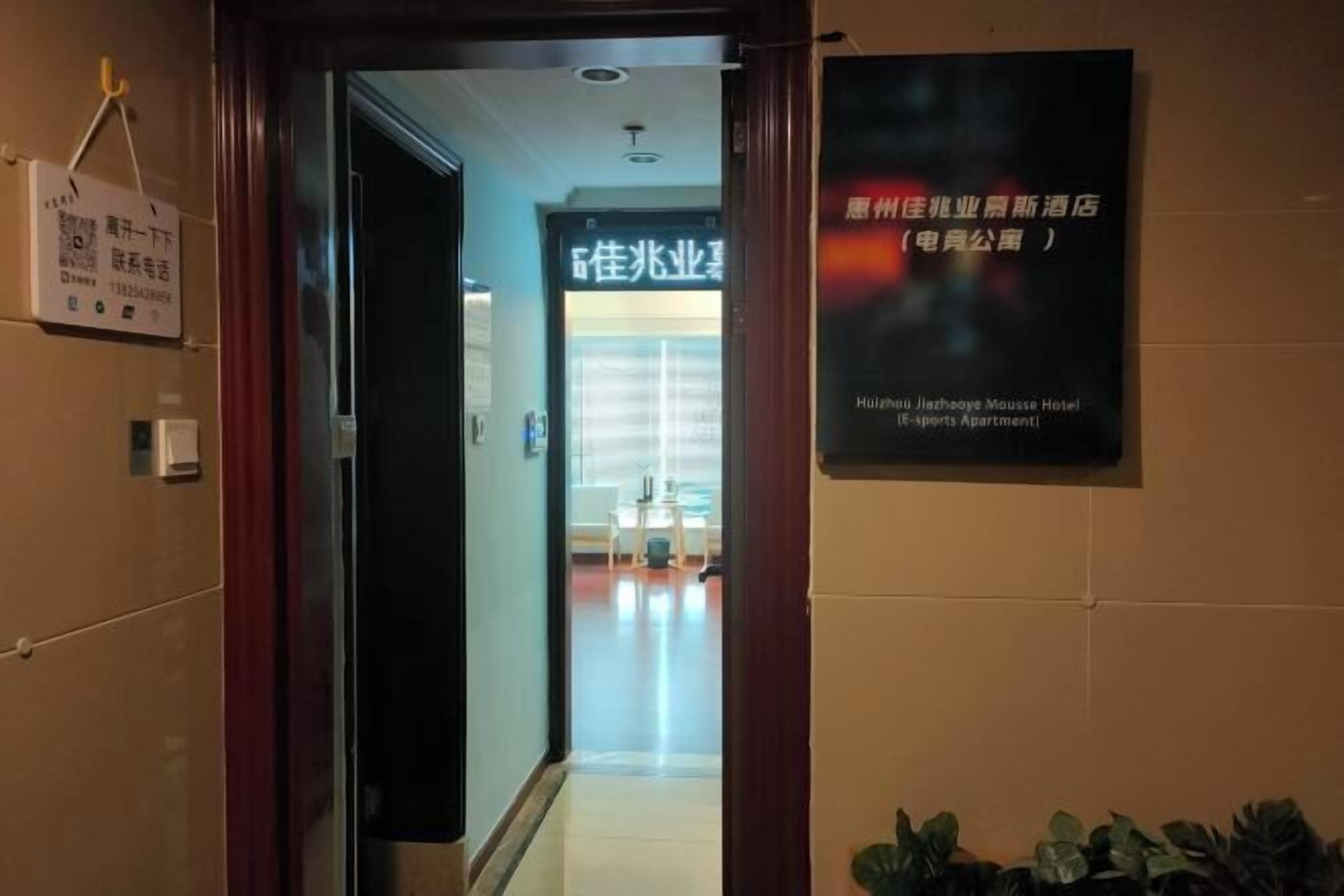 A hotel entrance with a sign indicating the Huazhou Jiazeheye Mousse Hotel (5-sports Apartment).