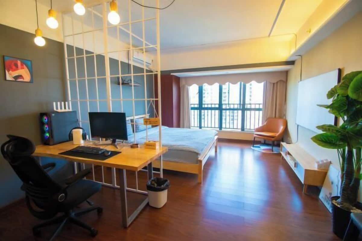 Une pièce comprenant un lit, un bureau, une chaise, un ordinateur et une grande fenêtre.