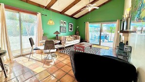 A living room with a sofa, chairs, a coffee table, a ceiling fan, and a large window with curtains. - Walk Downtown, 2 Large Mountain View Patios (Palm Springs)