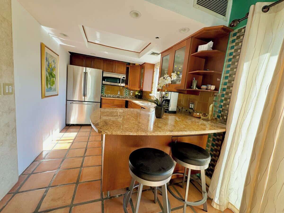 A kitchen with a stainless steel refrigerator, a microwave, and a granite countertop.