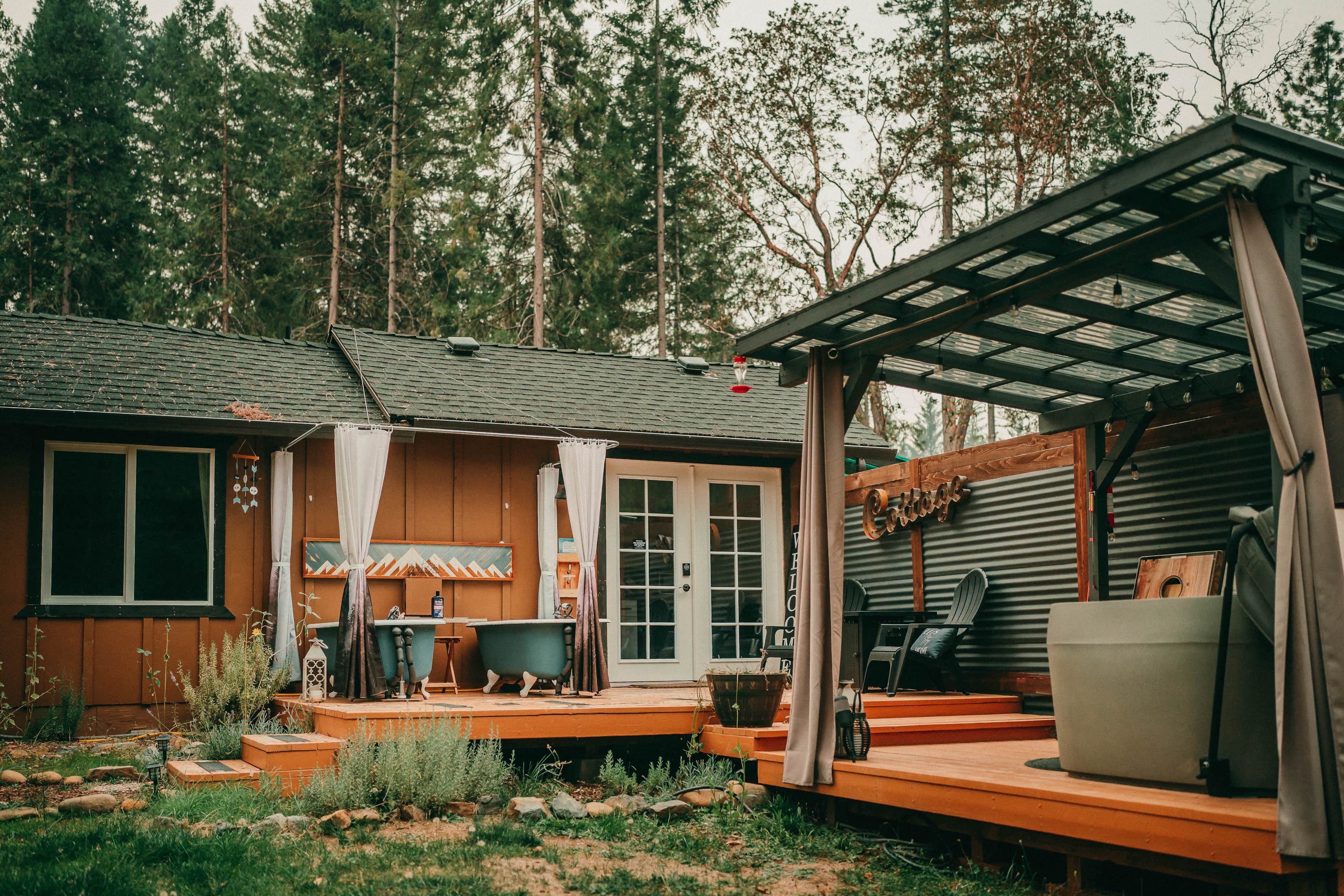 A rustic cabin with a porch, a hot tub, and a covered outdoor seating area.