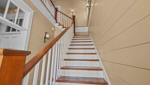 A staircase with wooden steps and white railings, leading to an upper floor.