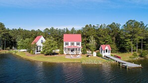 A lakeside property with a main house and a smaller cabin, surrounded by dense forest.