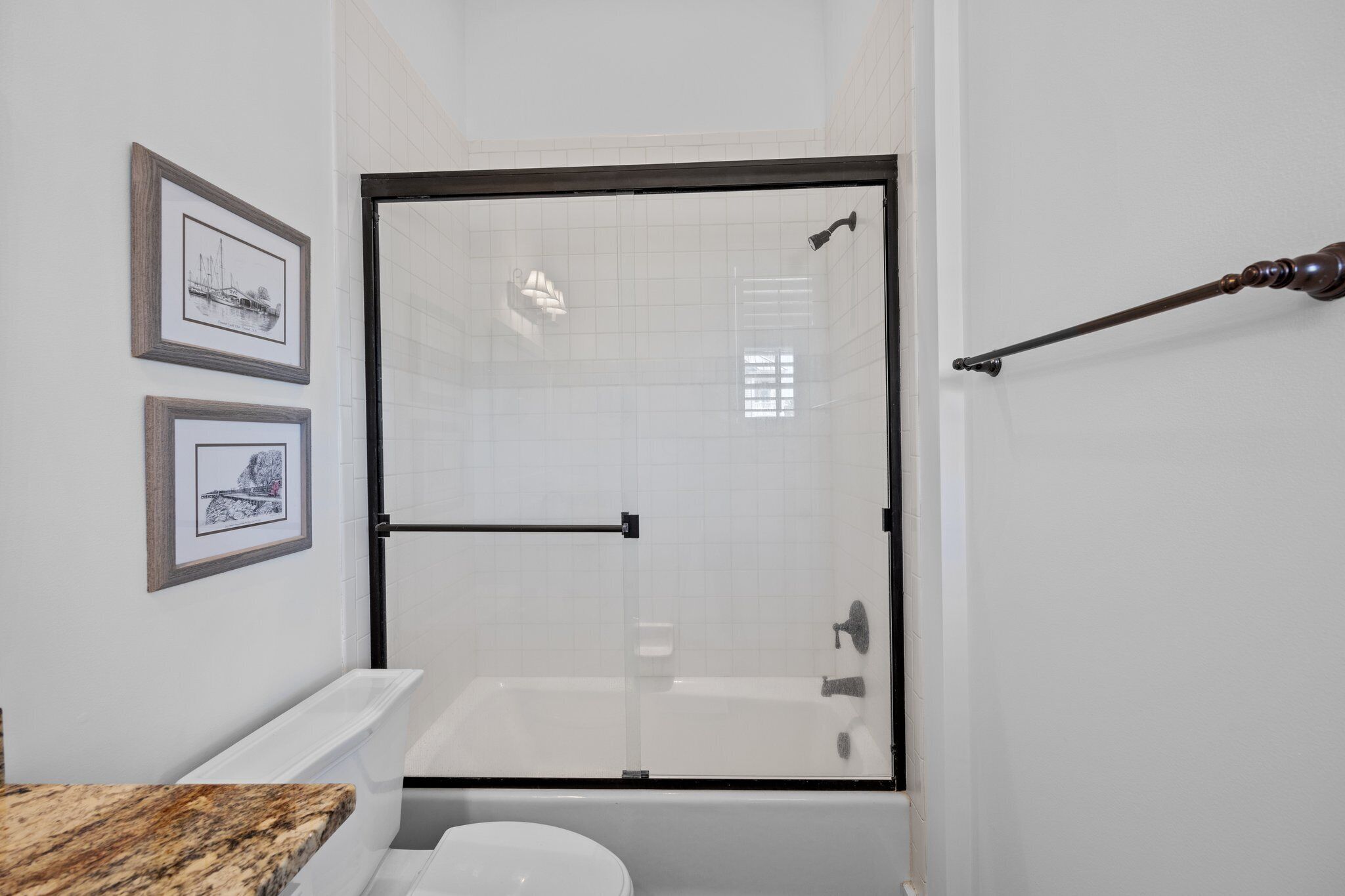 Une salle de bain moderne avec une douche à parois de verre, une baignoire blanche et un comptoir en marbre.