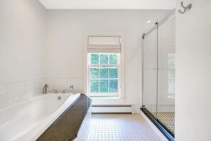 Een badkamer met een bad, een douche en een raam.