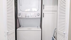 A compact, white laundry room with a front-loading washing machine and a dryer. - Newly built guest house with full kitchen and washer/dryer (Simi Valley)