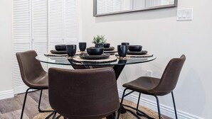 A dining area with a glass table surrounded by four brown chairs, a mirror on the wall, and a potted plant on the table. - Newly built guest house with full kitchen and washer/dryer (Simi Valley)