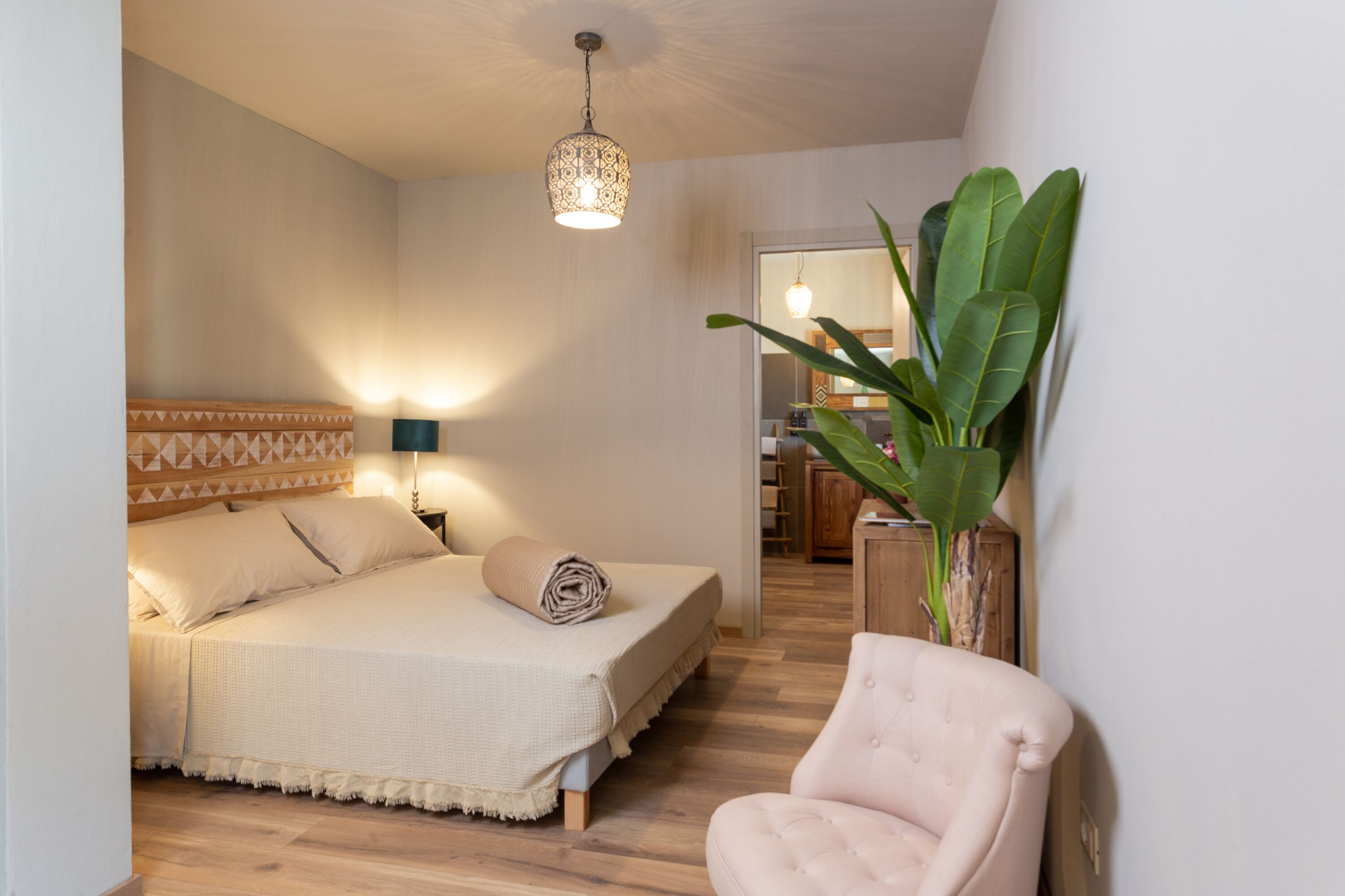 Ein Schlafzimmer mit Bett, Nachttischlampe und einer Topfpflanze.